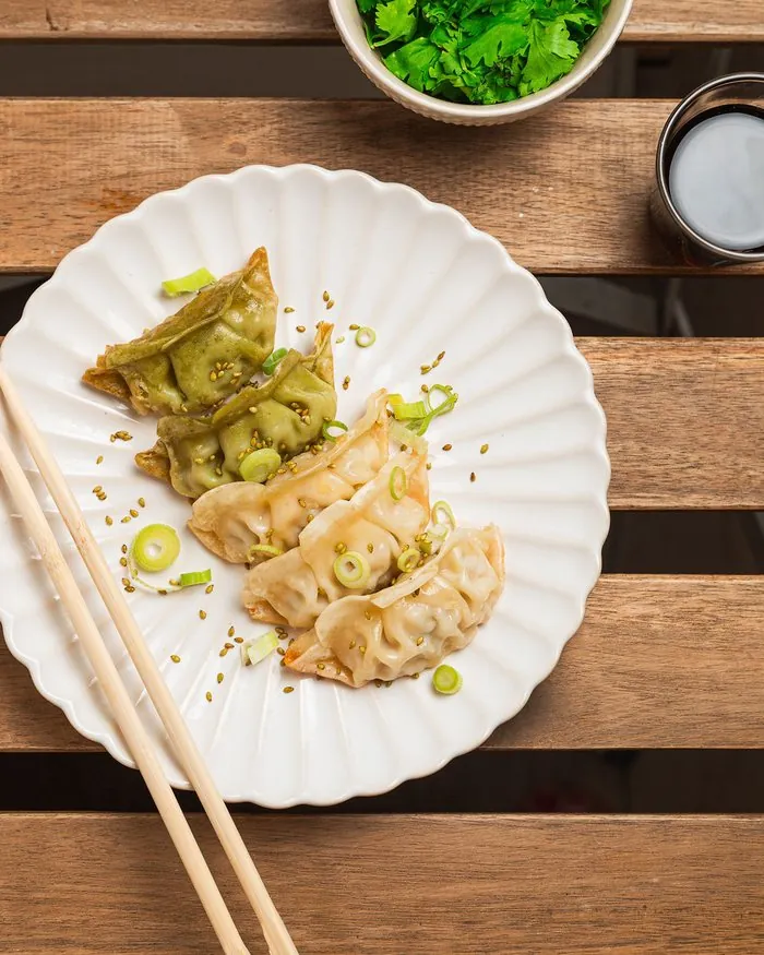 Hausgemachte Gyozas, goldbraun und mit Matcha-Tee, serviert mit Sesam und Frühlingszwiebel